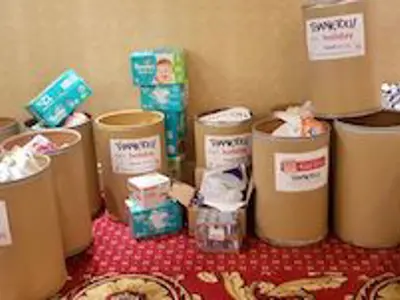 Collection bins labeled for donations are placed against a wall, filled with various items.